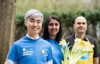 Three individuals smiling and holding flowers
